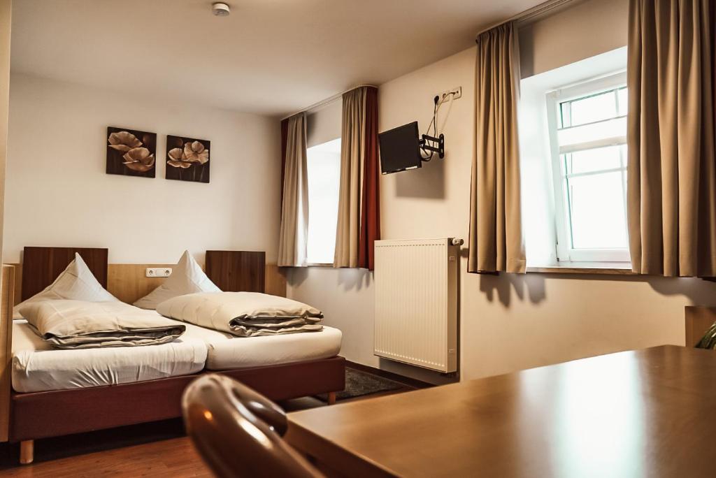 a bedroom with a bed and a table and a window at Zum Hopfenbauer in Rudelzhausen