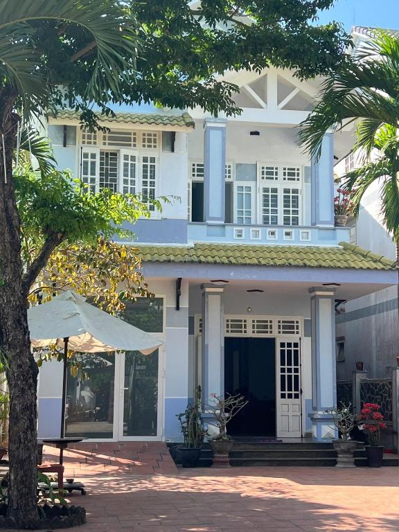 a white house with a tree in front of it at Vy Home in Thanh Ðông (1)