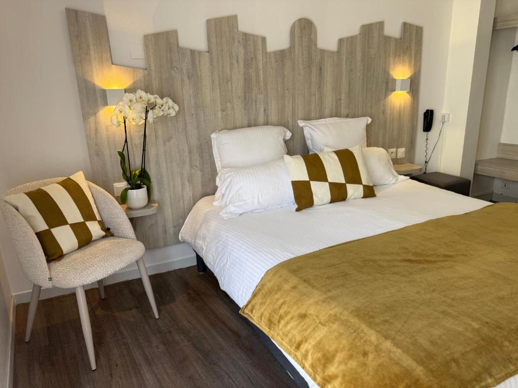 a bedroom with a large bed and a chair at Hotel Provencal in Saint-Raphaël