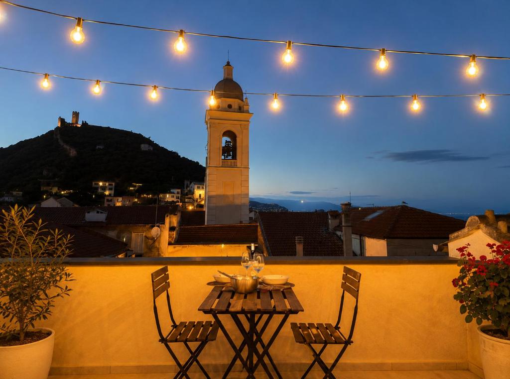 a table and chairs on a balcony with a clock tower at Ca' Du Marchin, Noli. in Noli