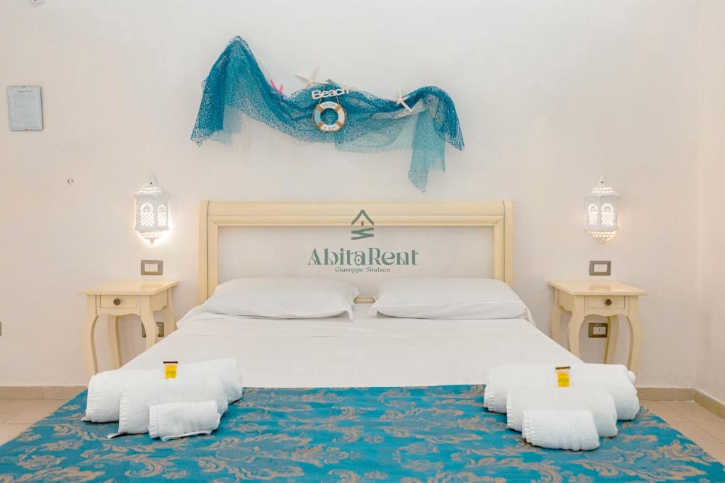 a bedroom with a large white bed with a blue blanket at Palazzo Piccioli in Gallipoli