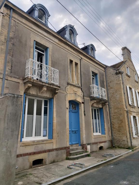 an old building with a blue door on a street at Villa Petit Pierre in Saint-Aubin-sur-Mer