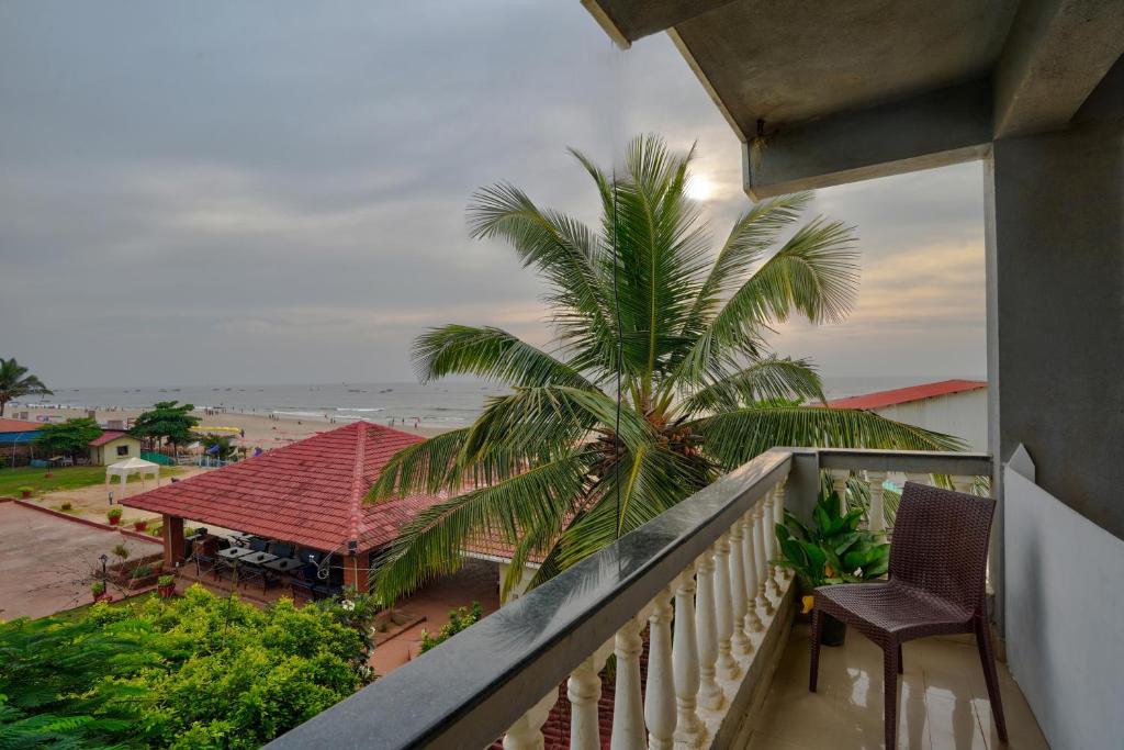 a balcony with a view of a palm tree and the ocean at Hotel Salty Waves Baga in Baga