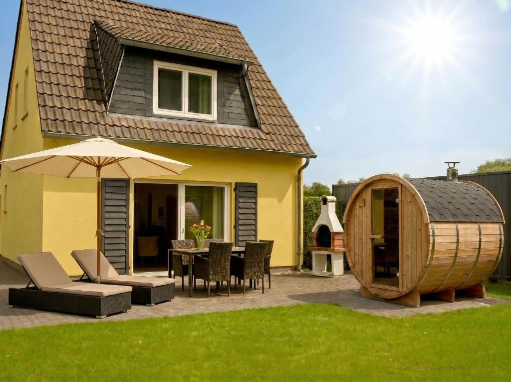 a patio with a table and an umbrella and a wooden barrel at Ferienhaus Seerose - Sauna, eingezäunter Garten, Hunde, 3 min zum See in Göhren-Lebbin
