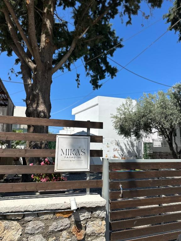 a sign on a fence in front of a tree at Mika's Paradise in Archangelos
