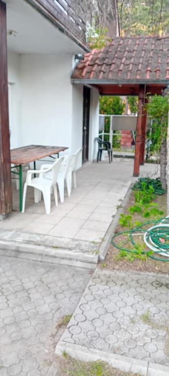 a patio with white chairs and a wooden table at Vila Sofija in Vinci