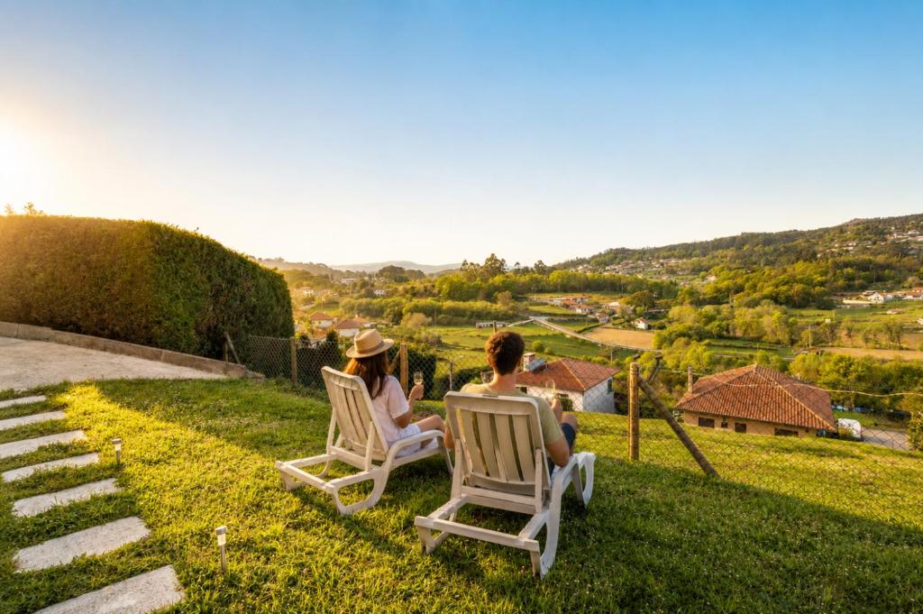 two people sitting in lawn chairs on the grass at Casa Outeiro 99 in Paredes de Coura