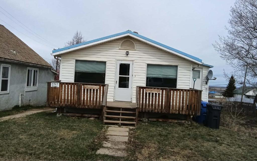 a small white house with a porch and a yard at Sword and Dove Rental in Spirit River