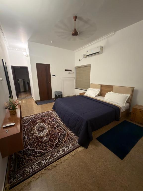 a bedroom with a bed with a blue blanket and a rug at The Golden, Apartrooms in Trivandrum