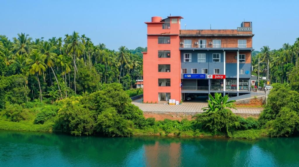 a building next to a body of water at RIVULET River Side Budget Business Class Hotel in Mukkam