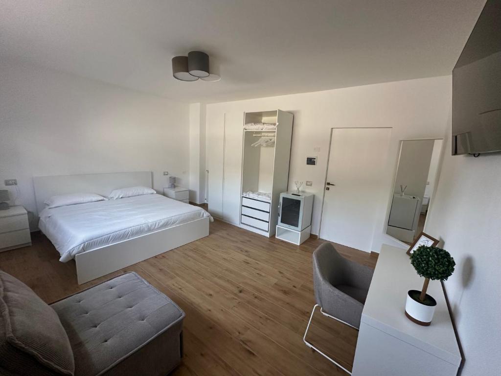 a white bedroom with a bed and a chair at Residenza Dottavio in Montenero di Bisaccia
