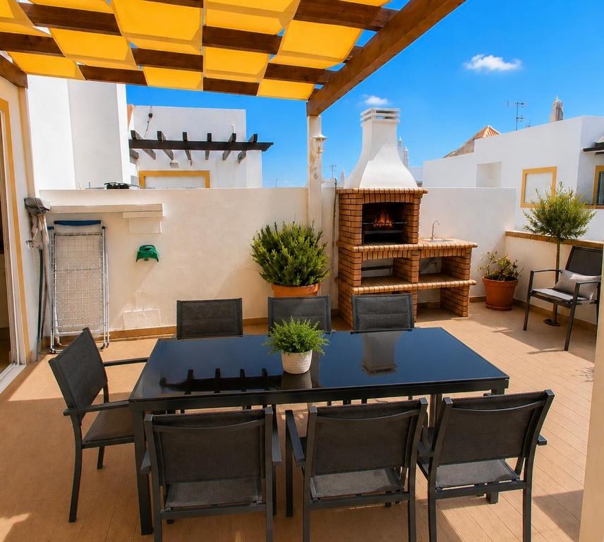 a patio with a table and chairs and a fireplace at Cabanas Terraces - Pool and seaview in Tavira