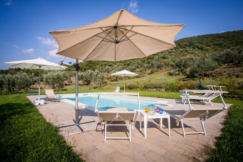 una piscina con sombrilla y sillas y una mesa con en San Martino agli Ulivi, en Cortona