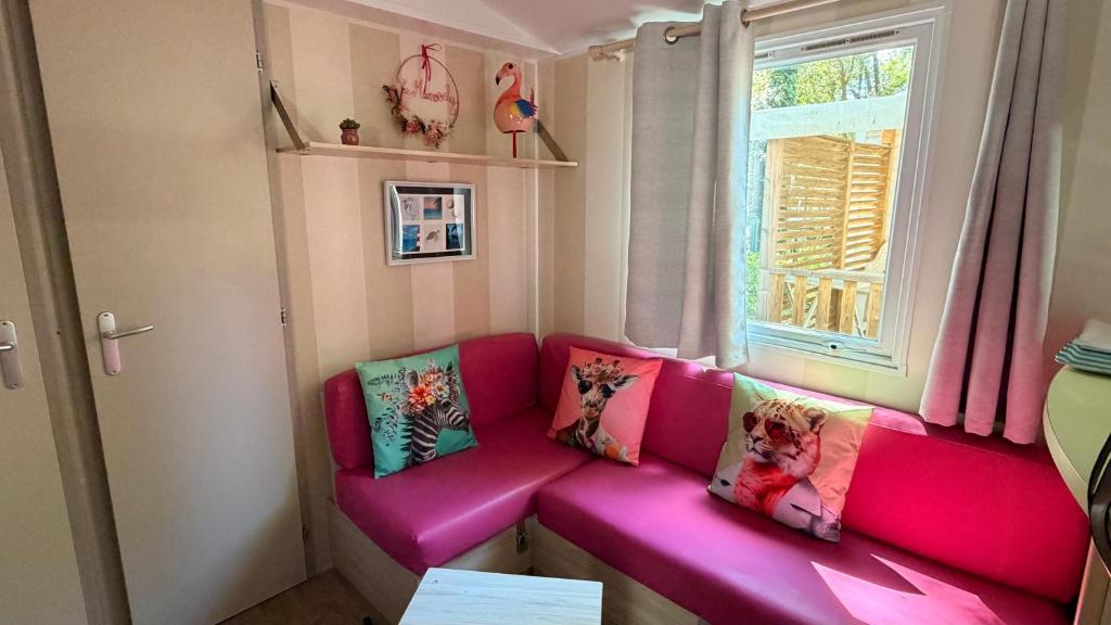 a pink couch in a room with a window at Mobil-home Le Manosely confort 6 pers Climatisé-Plages à proximité in Agde