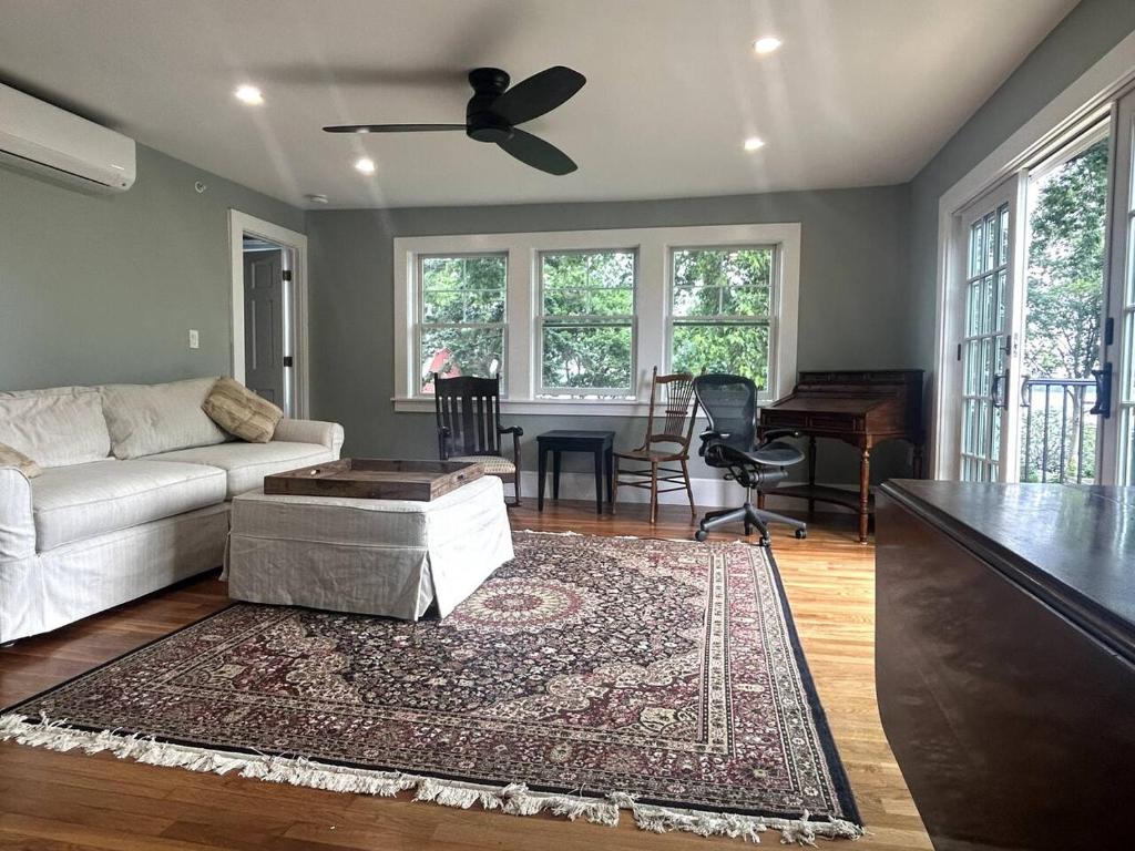 a living room with a couch and a ceiling fan at Steps to Derby Wharf and Gables. in Salem