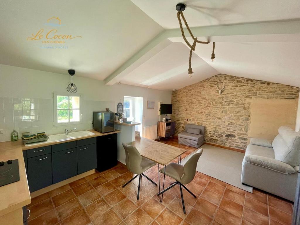a kitchen and living room with a table and a couch at Le Cocon des Forges in Talmont