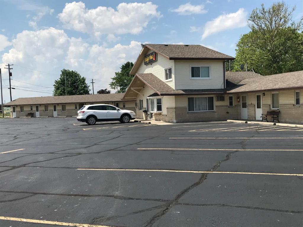 a car parked in a parking lot in front of a building at The Perrysburg Budget Inn in Millbury