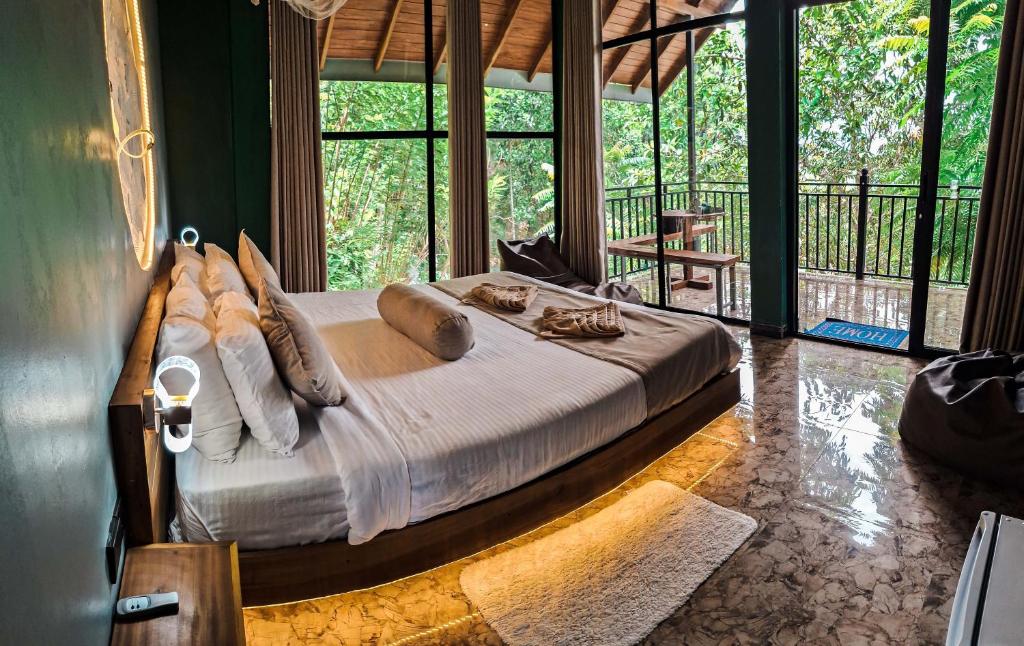 a bedroom with a large bed in a room with windows at Nice View Guest House & Restaurant in Ella