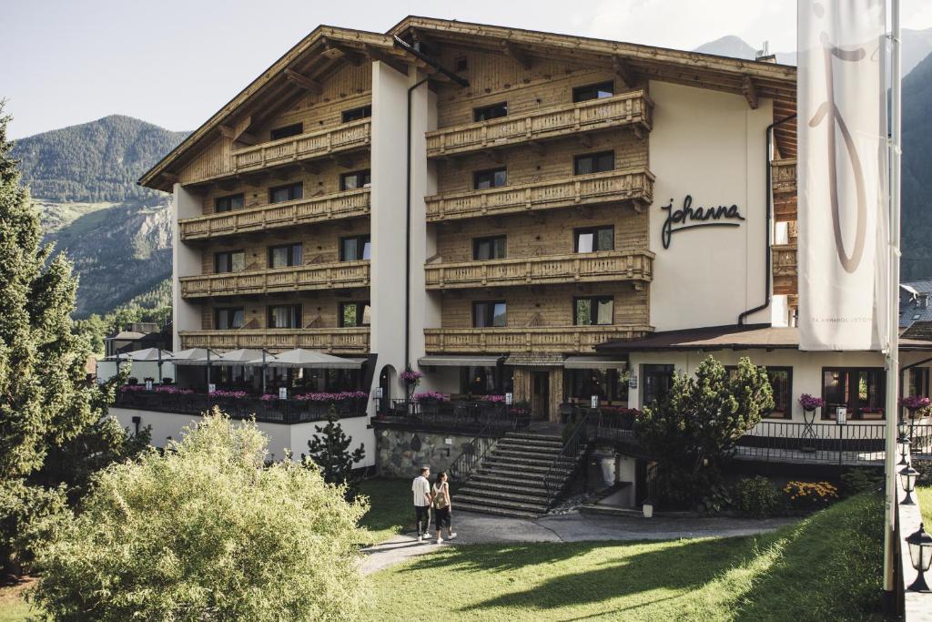 a large building with two people standing in front of it at Hotel Johanna mitten im Ötztal in Umhausen