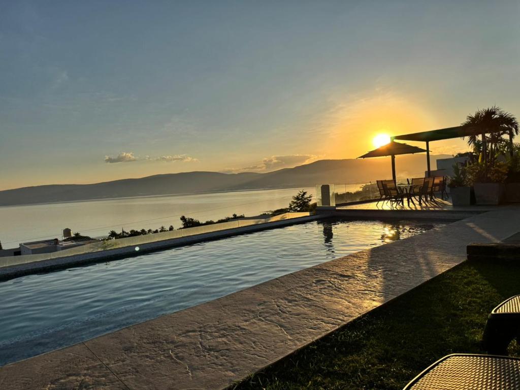 a swimming pool with the sun setting over the water at Vistas del Angel in San Juan Cosalá