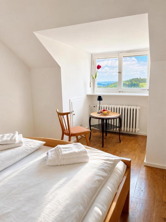 a bedroom with two beds and a table and a window at Landhaus Schönblick in Bad Kohlgrub