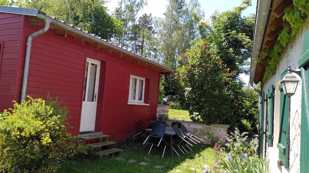 a red house with two chairs sitting outside of it at La cabane Rouge in La Queue-dʼHaye