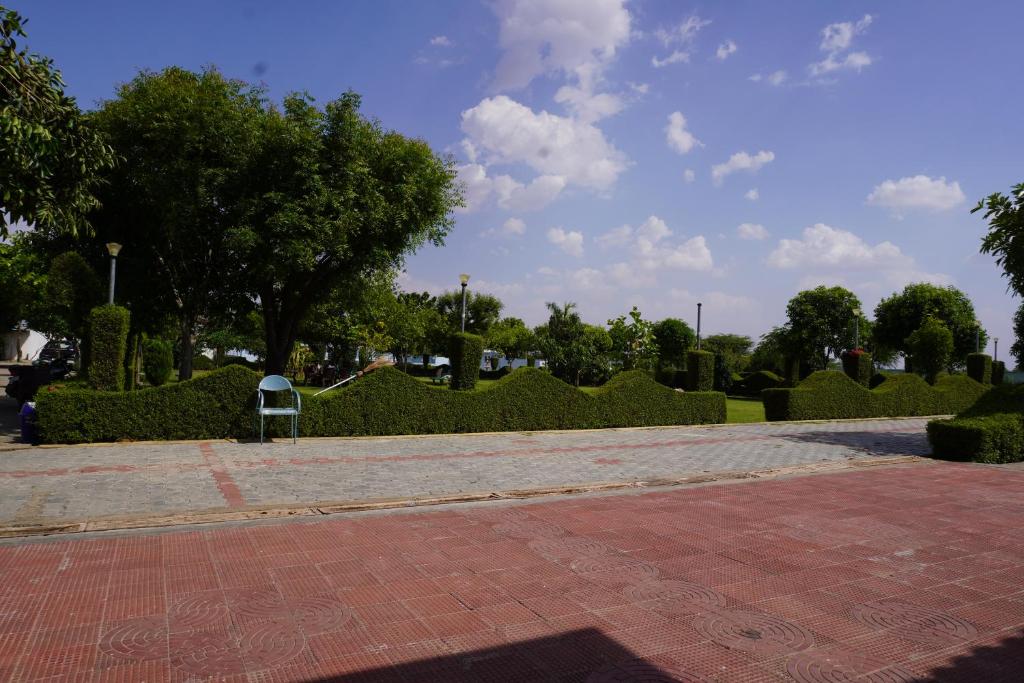 a park with hedges and a brick walk way at Hotel Raj Resort and Pool in Dogeta