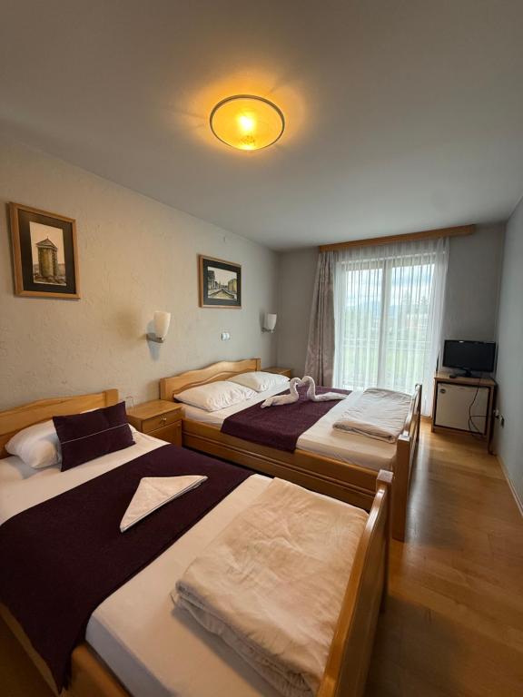 a bedroom with three beds and a television at Motel Alibey in Bugojno