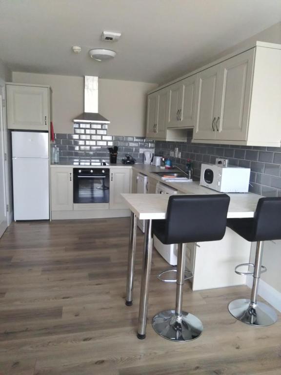 a kitchen with white cabinets and a table and chairs at Codladh Samh Apartment No 2 in Templemore