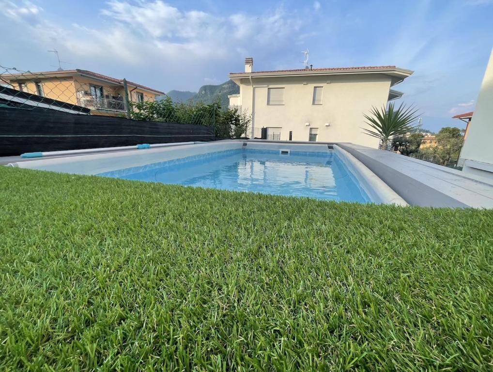 a swimming pool with grass in front of a house at ABC Holiday in Salò
