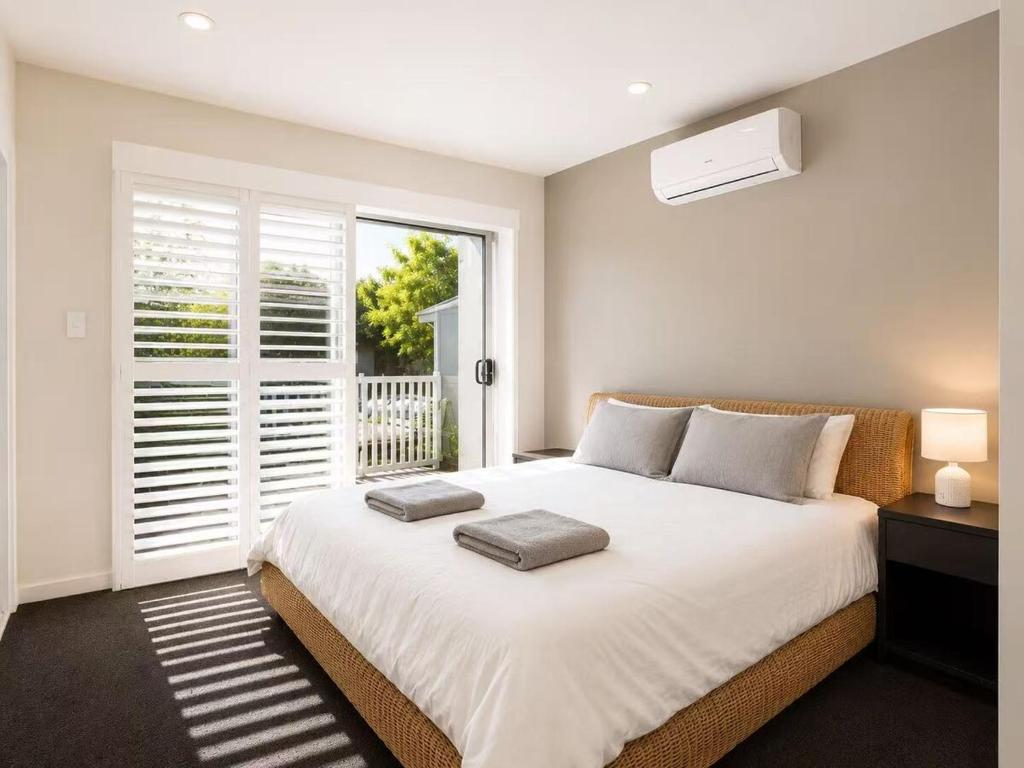a bedroom with a large white bed with a window at 21 Pimpama Home in Pimpama