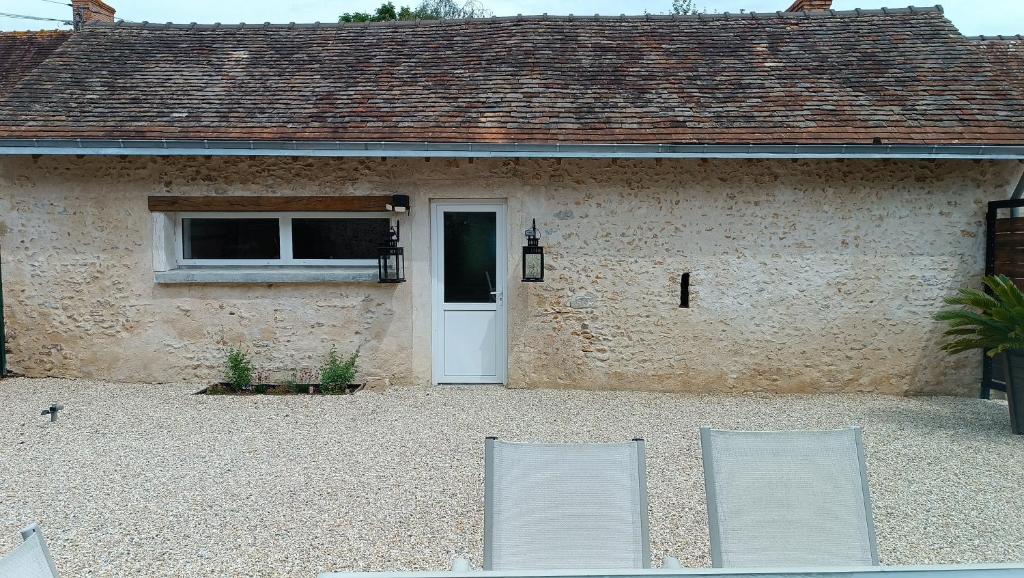 two chairs in front of a building with a door at Douce Campagne in Clermont-Créans