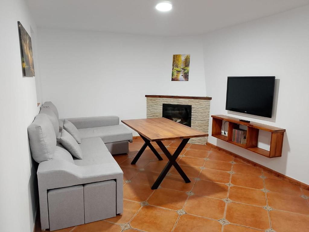 a living room with a couch and a table and a television at Casa La Piedra in Constantina