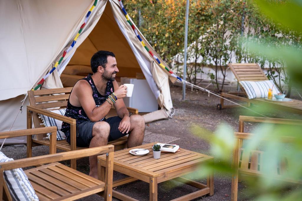 a man sitting in a tent with a cup of coffee at Nisi Glamping in Paralia Rachon