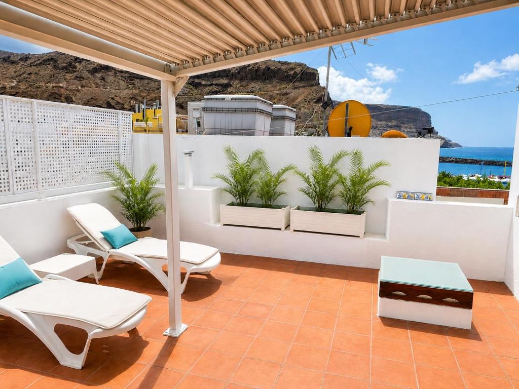 a patio with white chairs and a basketball hoop at Deluxe Mogán Beach Apt 1 in Puerto de Mogán