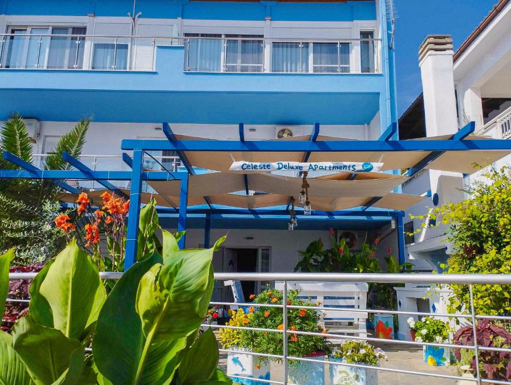 a blue building with a table and chairs and plants at Celeste Deluxe Apartments in Skala Potamias