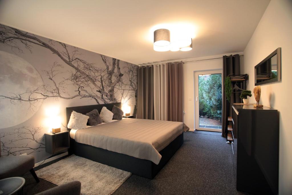 a bedroom with a bed with a tree mural on the wall at Blackhillhouse - Moderne Auszeit im Harz in Osterode