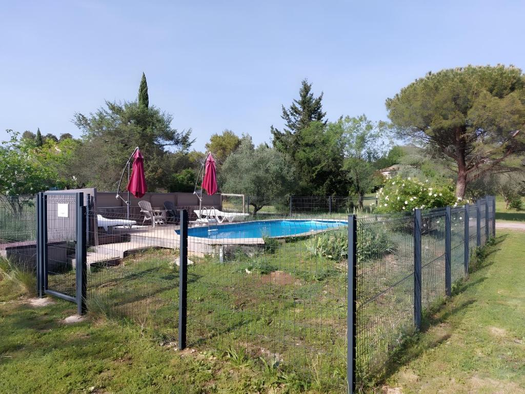 a fence around a swimming pool in a yard at Gîte Chêne ou Murier in Les Vans