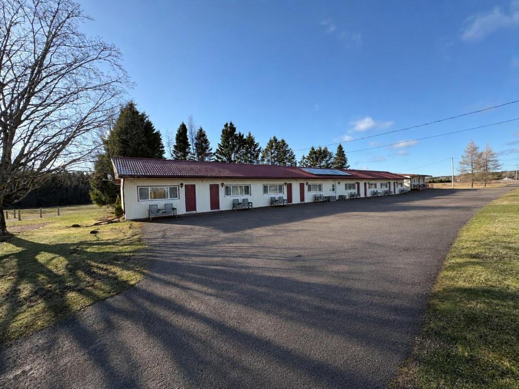 a large white building with red trim on a road at The Sunshine Inn in Parrsboro