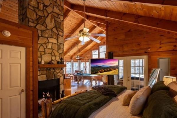 a bedroom with a large bed and a stone wall at Cozy Cabin Retreat Near Helen Hot Tub Fireplace in Sautee Nacoochee