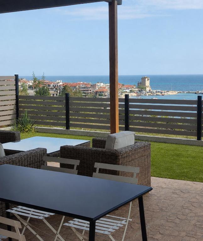 a table and chairs on a patio with a view of the ocean at Ouranoupolis View Point in Ouranoupoli