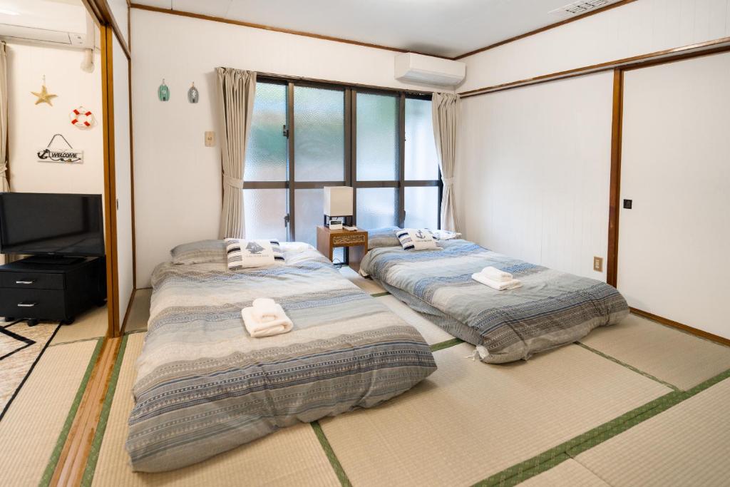two beds in a room with a window at Green Hights Residence-107 in Naha