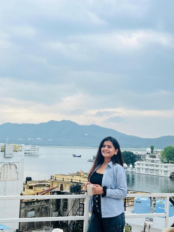 a woman standing on a balcony with a view of the water at Old Skool Udaipur - 20 Meter From Lake in Udaipur