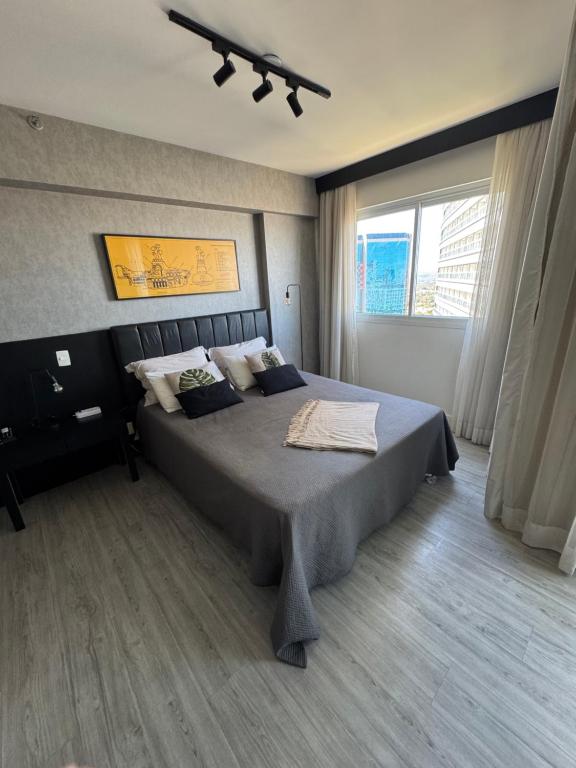 a bedroom with a large bed and a large window at Apartamento moderno e aconchegante com vista para a Esplanada in Brasília