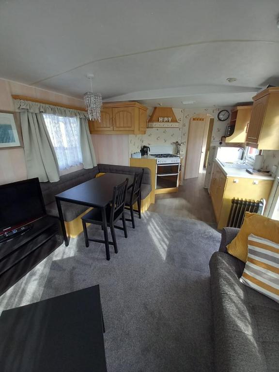 a living room and kitchen with a table and chairs at GnT Caravan lets in Anderby