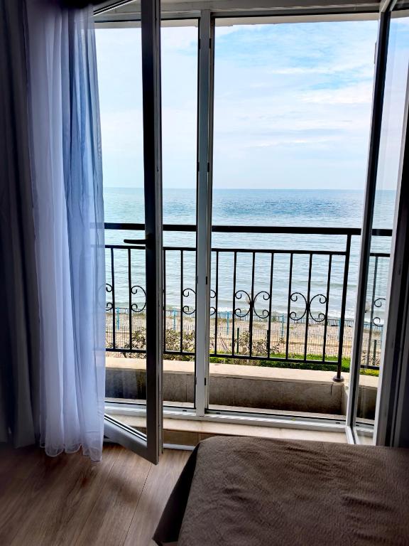 a bedroom with a view of the ocean from a balcony at DL Apartments in Aheloy