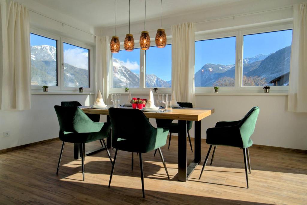 a dining room with a table and chairs and windows at Dangos Mountainview Gosau in Gosau