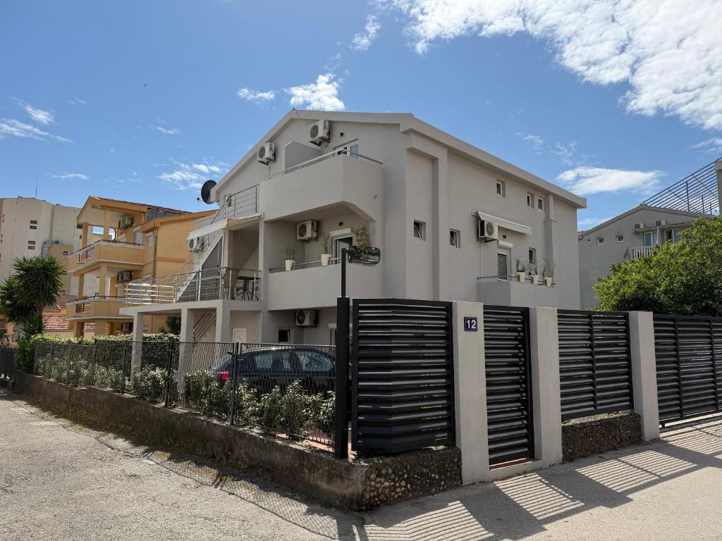 a white building with a fence in front of it at Guest House Jasna in Budva