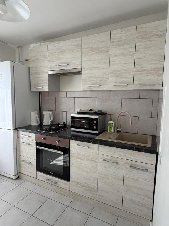 a kitchen with wooden cabinets and a sink and a microwave at NV Apartments in Volodymyr-Volynskyi