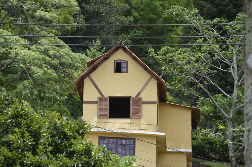 ein gelbes Haus mit einem Fenster darüber in der Unterkunft Chalé da Jajá -Um Lugar Inteiro pra VC in Miguel Pereira